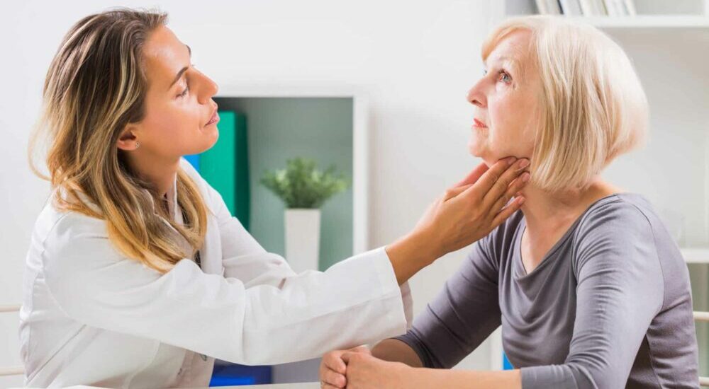 médecin palpant la thyroïde d'une patiente